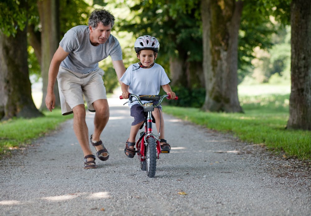 man teaching boy to ride a bike