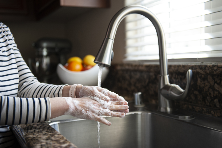 Person washing hands in kitchen sink 