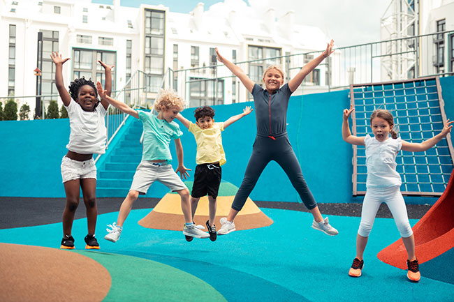 Children happily jumping around on playground equipment.