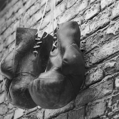 Black and white boxing gloves hanging on brick wall