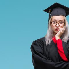 A blonde female student wearing glasses holding her hand up to her mouth with a look of anxiety on her face