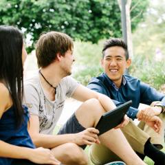 students sitting on a field having a light hearted conversation