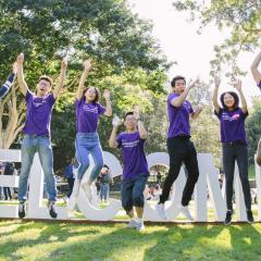 Students jumping up in front of a welcome sign