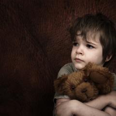 child hugging bear looking sad 