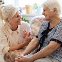 Elderly mother and daughter talking on couch happily