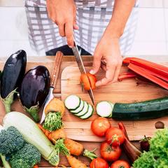 A person preparing food by cutting vegetables on a board.