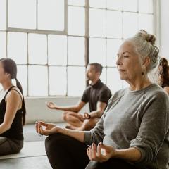A group of people in a bright studio environment doing guided mediation