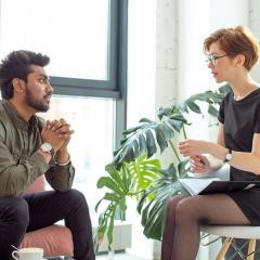 Two people engaged in conversation while seated on a sofa