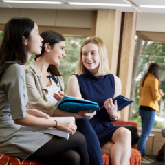 Three female presenting students sitting talking