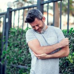 Man holding his elbow promoting a research study aimed at understanding tennis elbow