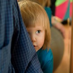 young child hiding behind adult