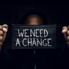 person holding mask that says 'we need a change'
