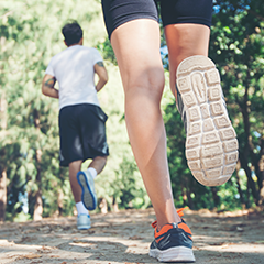 Two people running on dirt path