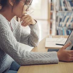 Universiyt student studying in library on tablet