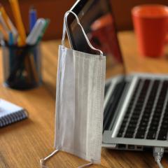laptop with a disposable face mask hanging on the corner