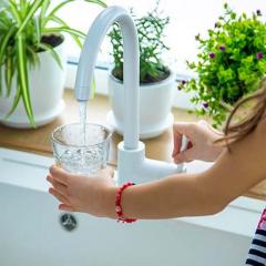 Young girl filling glass with tap water