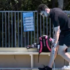 A man walking along a pool holding a device in the water
