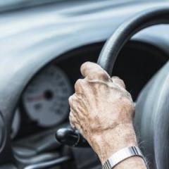 aged hands on a steering wheel