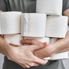 person holding many rolls of toilet paper