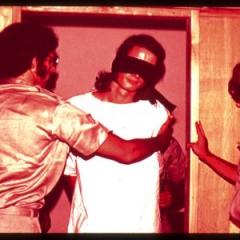Guards with a blindfolded prisoner in the Stanford Prison Experiment, 1971