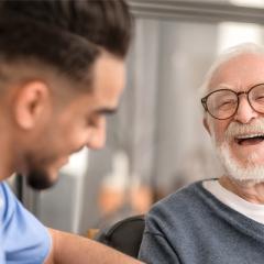 A male doctor with an elderly man laughing