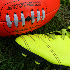 AFL ball and yellow football boots on grass