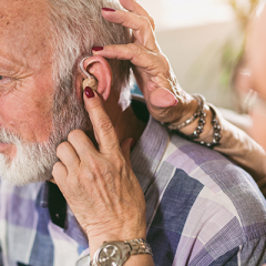 Elderly man getting a hearing aid fitted