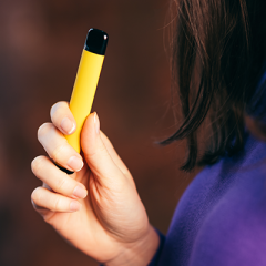 Young woman holding yellow vape