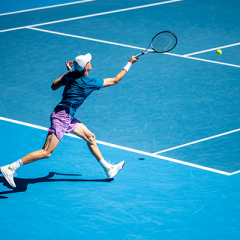 Man playing tennis on blue court
