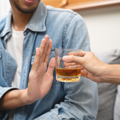 male holding up hand rejecting an offer of an alcoholic beverage