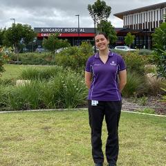Woman in purple shirt standing in front of the Kingaroy Hospital building.