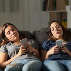 two young ladies lounging on couch on phones