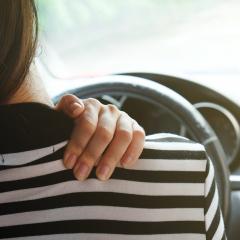 woman holding shoulder whilst driving 