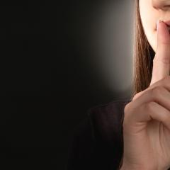 woman pressing finger to mouth