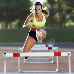 Female athlete jumping over hurdles