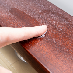 Finger swiping dust off wooden furniture 