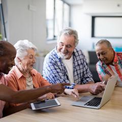 a group of older people using technology around a table