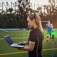 Female UQ academic monitoring laptop while athlete runs in background