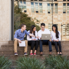 Four students sitting on steps