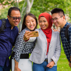 Four international students taking a selfie with a mobile phone