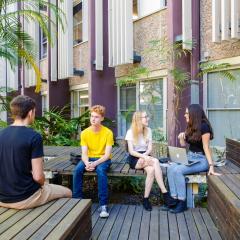 Students sitting on a wooden bench talking