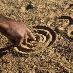 man drawing dreamtime story in sand 