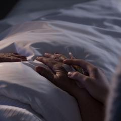  a hand comforting someone on a hospital bed