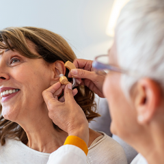 Doctor fitting woman with hearing aide