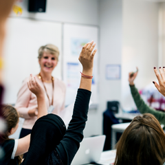Teacher at front of class with student's hands raised 