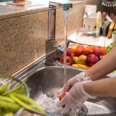 Person washing vegetables in kitchen sink 