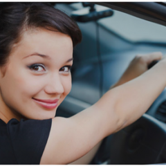 Young girl smiling in driver's seat of car