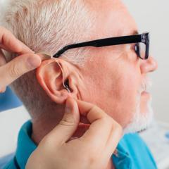 elderly man having hearing aid fitted